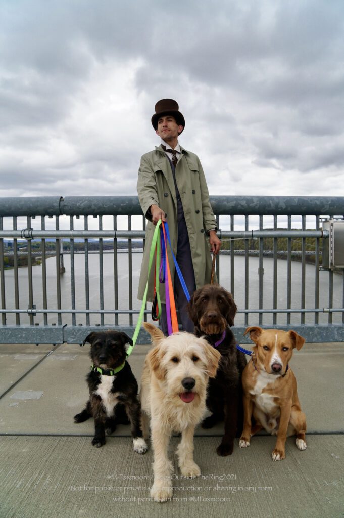 A man with a tophat handling four dogs