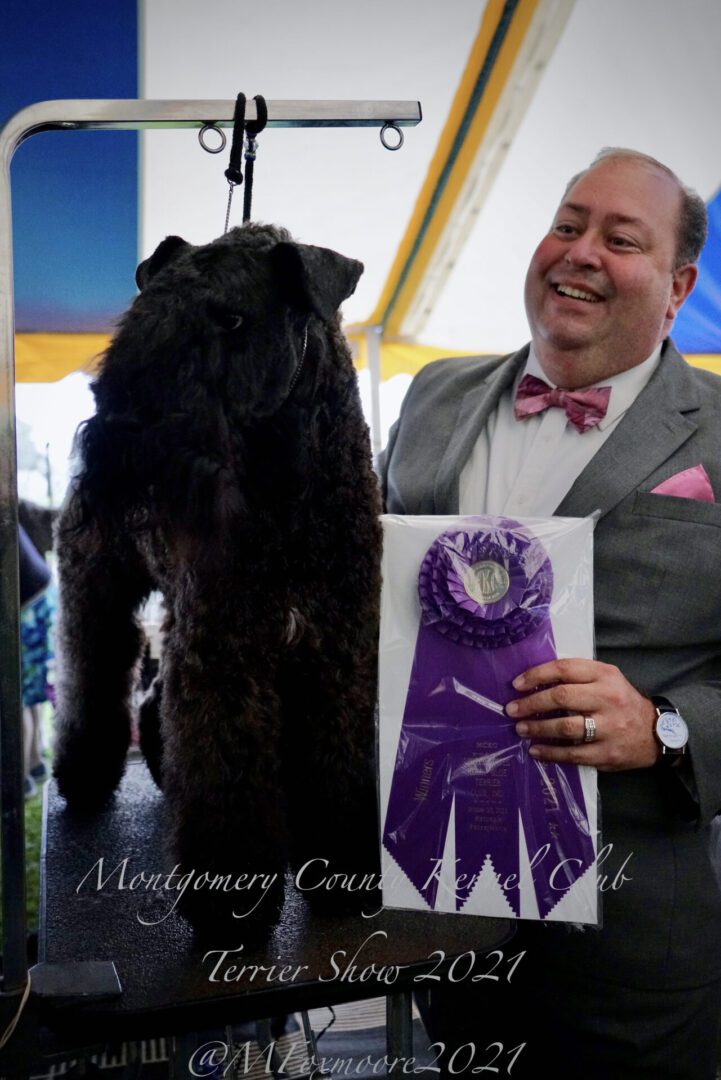 A man holding an award for his Terrier dog