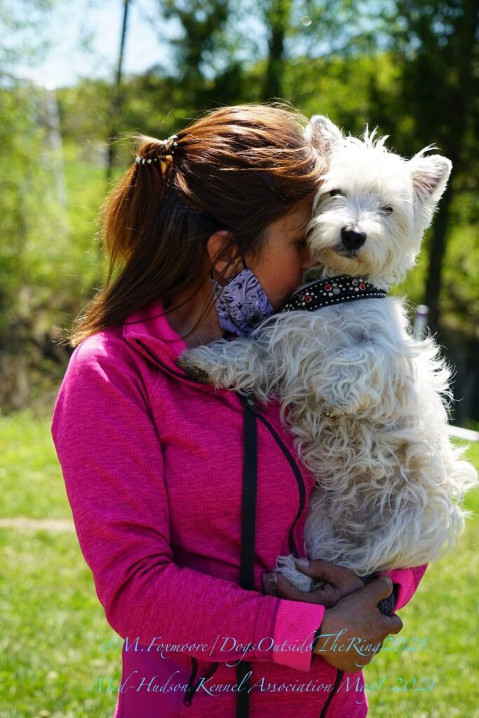A woman in pink hugging her dog
