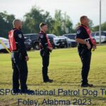 Three police officers in red and black uniforms watching an event attentively at the uspca national patrol dog trial in foley, alabama, 2023.