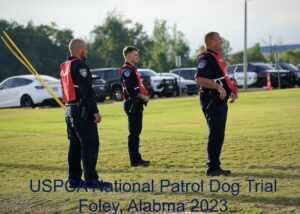 Three police officers in red and black uniforms watching an event attentively at the uspca national patrol dog trial in foley, alabama, 2023.