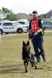 A police officer with a canine running at a uspca national patrol dog trial event in foley, alabama, 2023.