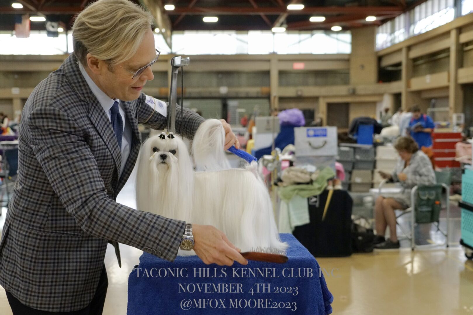 A Man Standing Beside a Dog With Long White Fur